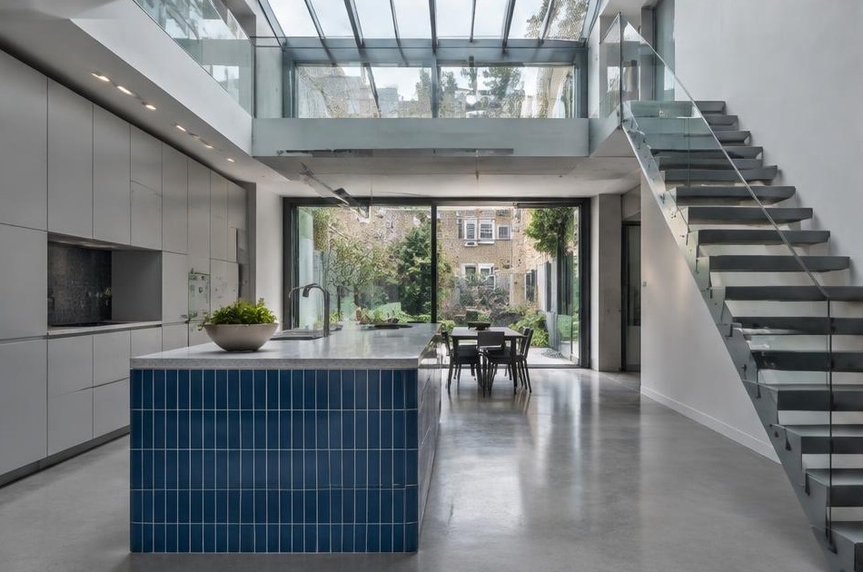 Contemporary kitchen with an open staircase and glazing onto a residential garden in Vauxhall