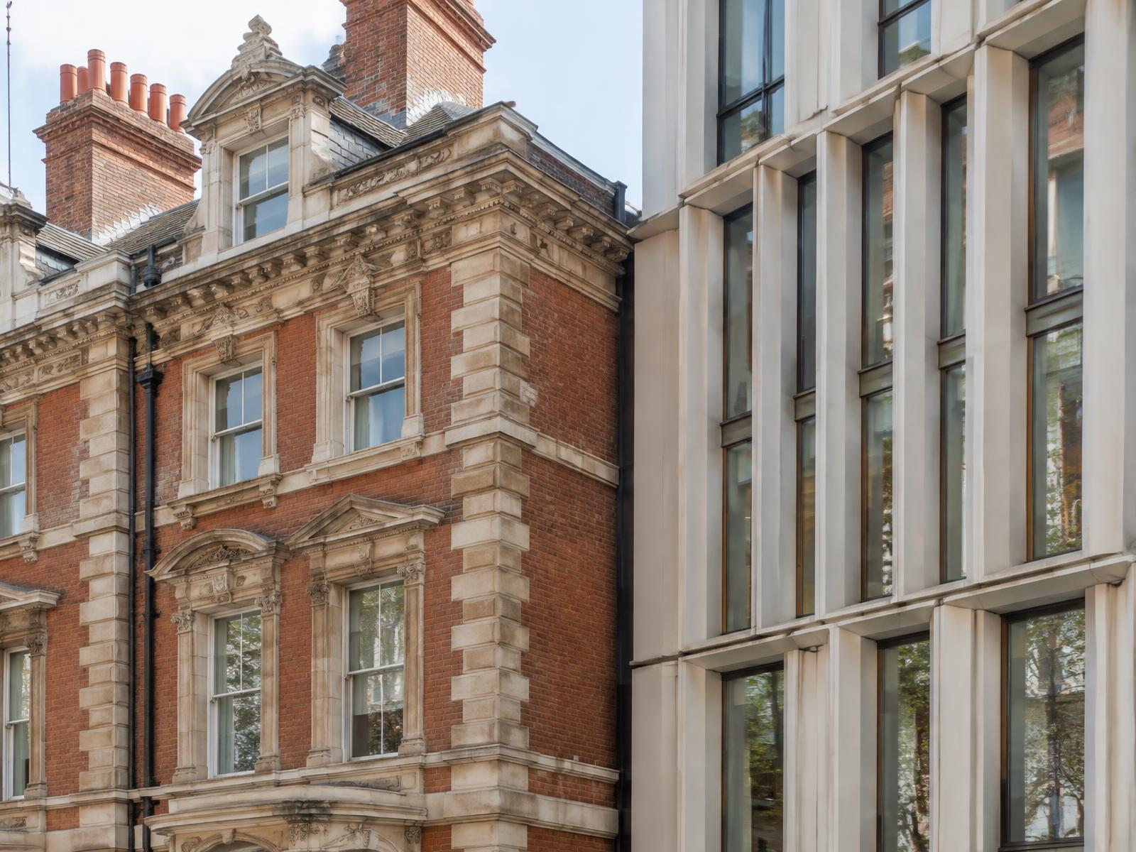 Red-brick and stone Victorian mansion block directly beside a contemporary pale-finned glass building in Victoria