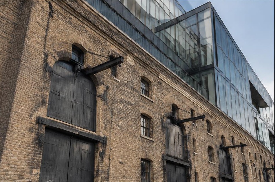 Retained original facade beside a dominant contemporary glazed addition in Wapping