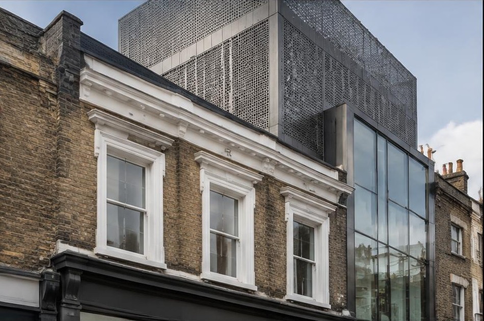Retained original facade beside a dominant contemporary glazed addition in Whitechapel