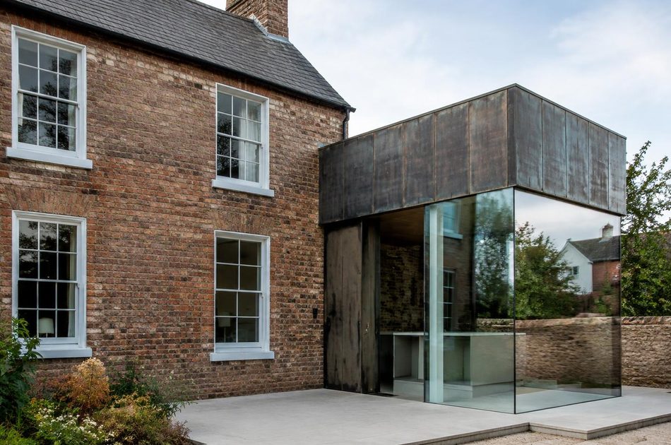 Georgian brick cottage beside a bronze and glass extension in Wimbledon