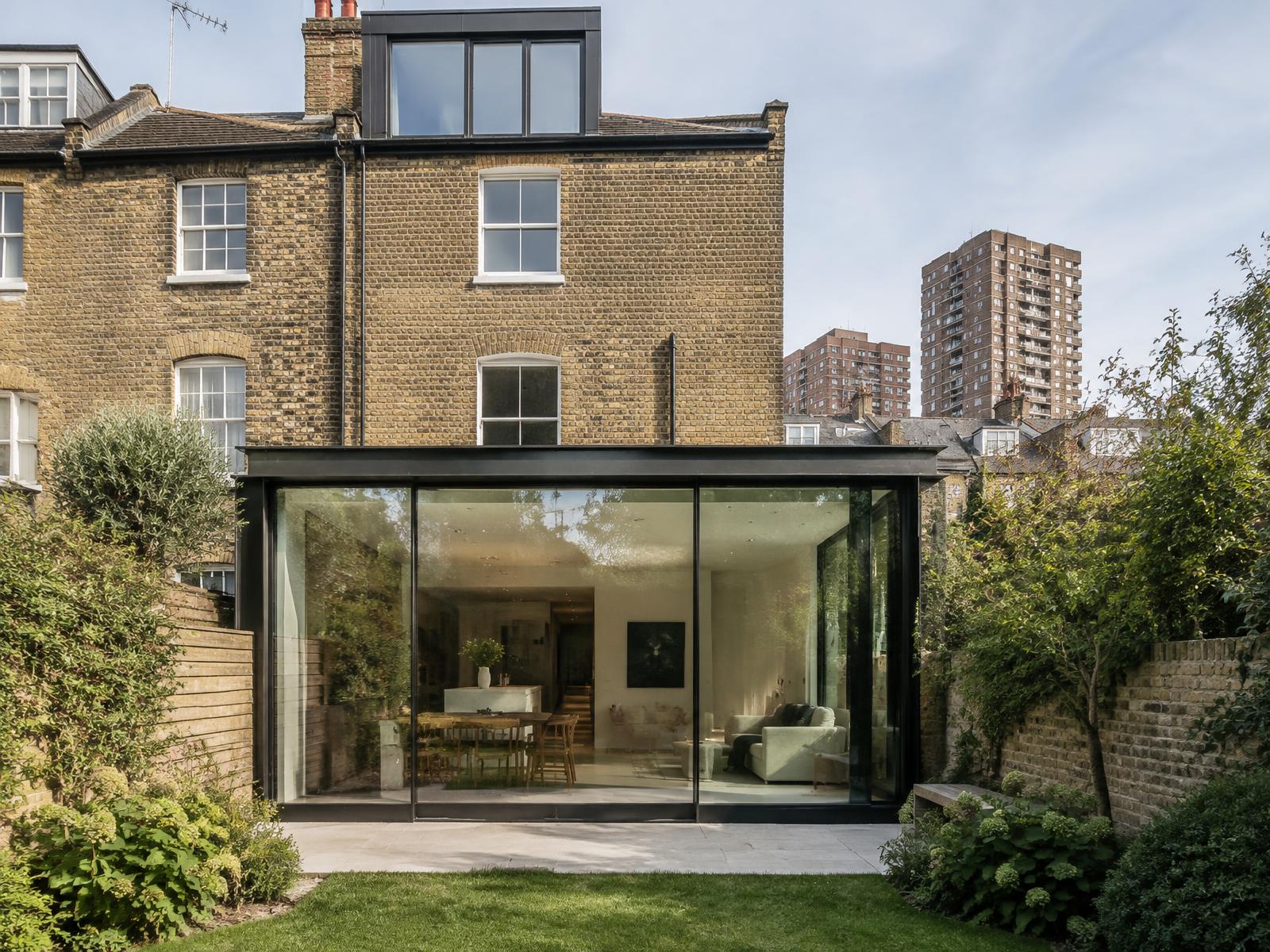 Victorian brick terrace house with a black-framed glass rear extension and estate towers beyond