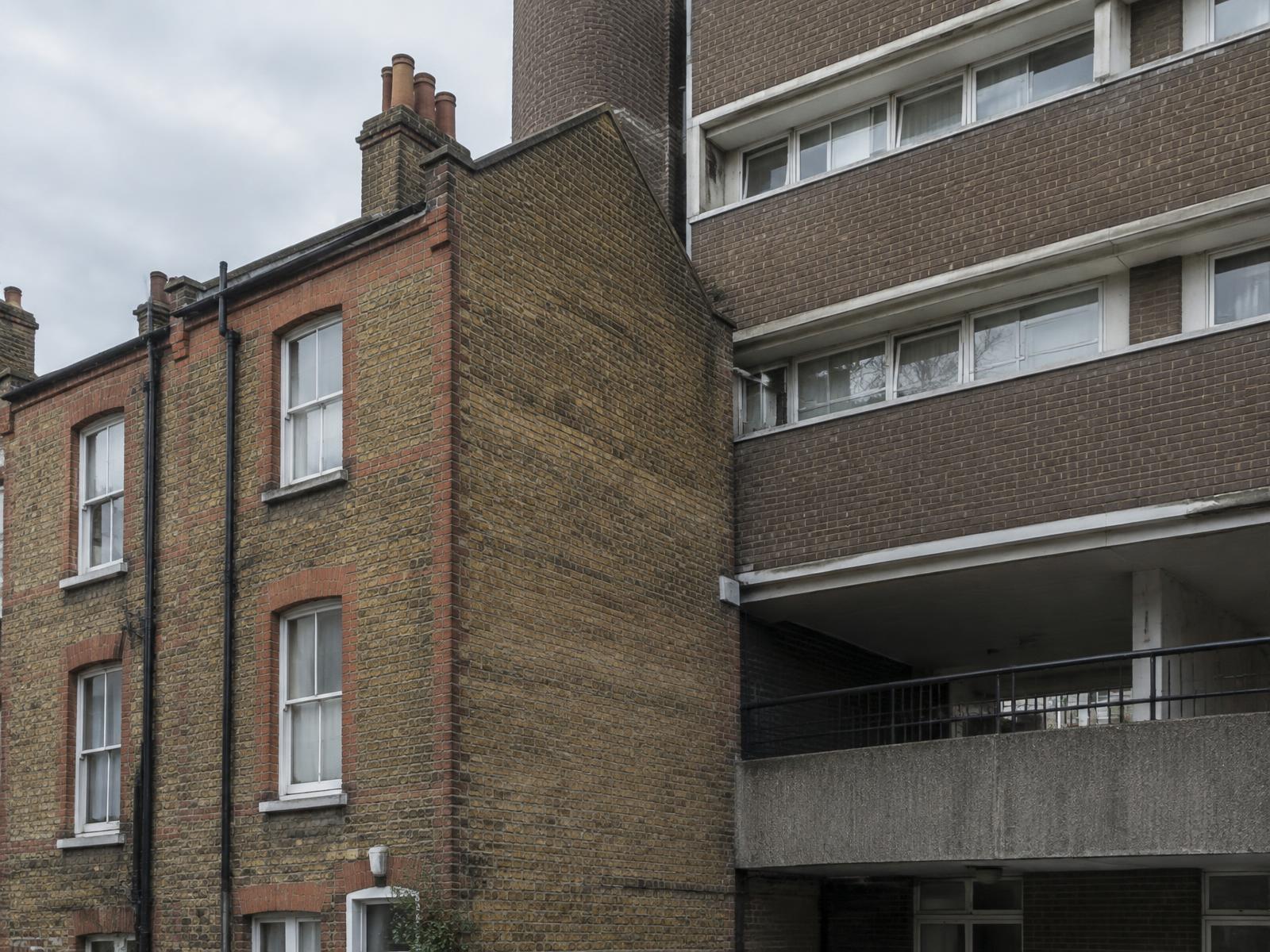 Victorian brick terraced house directly beside a 1960s modernist brick estate block with a concrete walkway
