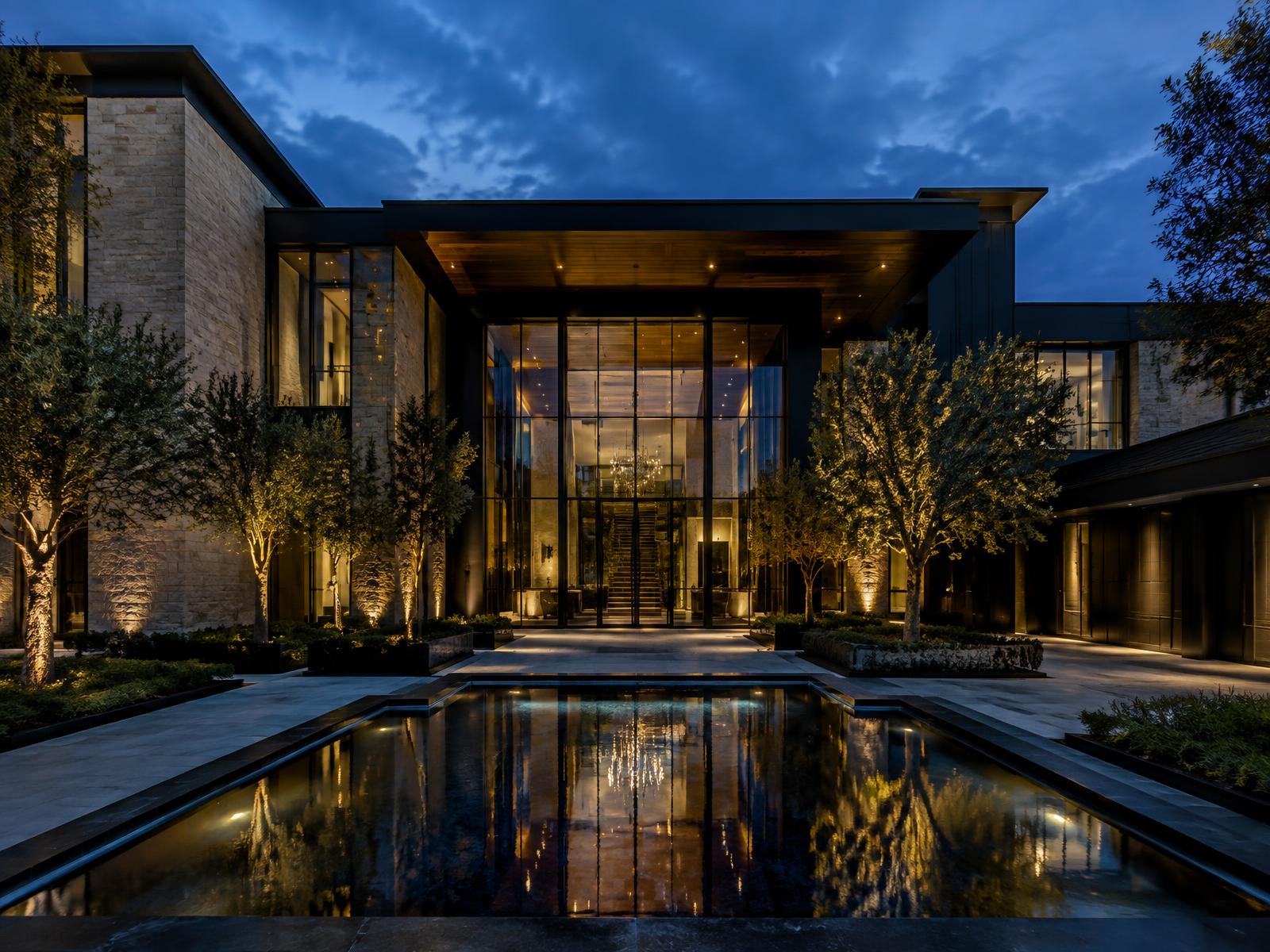 Generic contemporary stone mansion with double-height glazed entrance hall at blue hour